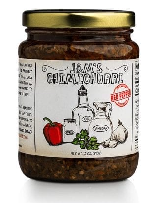 This is a jar of J&M's Chimichurri labeled as "Red Pepper." The packaging showcases an artisanal aesthetic, characterized by hand-drawn illustrations of its core ingredients, including oil, vinegar, spice, garlic, and notably, a red pepper which differentiates this variant from the original. The red "Red Pepper" badge on the label suggests that this particular version of the chimichurri sauce offers a mild sweet taste, enhancing its flavor profile. The label confirms that the net weight of the product is 12 oz (340g). The design consistently emphasizes a sense of authenticity and tradition, with the richly textured contents promising a robust and zesty experience. The added illustration of the red pepper hints at a sweeter, perhaps more adventurous take on the classic chimichurri sauce.